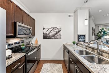 A kitchen with a black granite countertop and a white sink. at Bridge at Indigo, Austin, TX